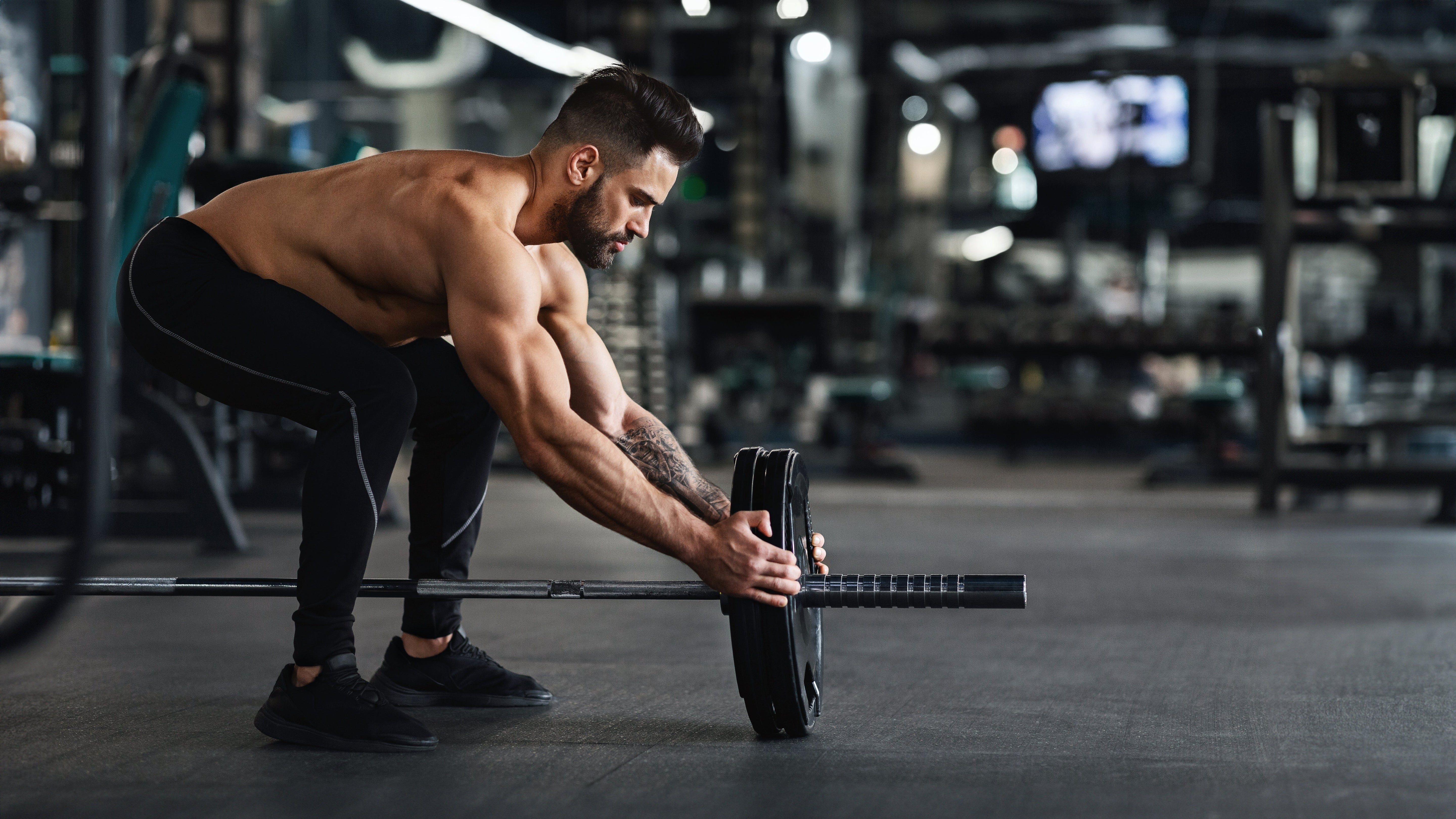 Ascari and Man adjusting a Olympic bar with weights